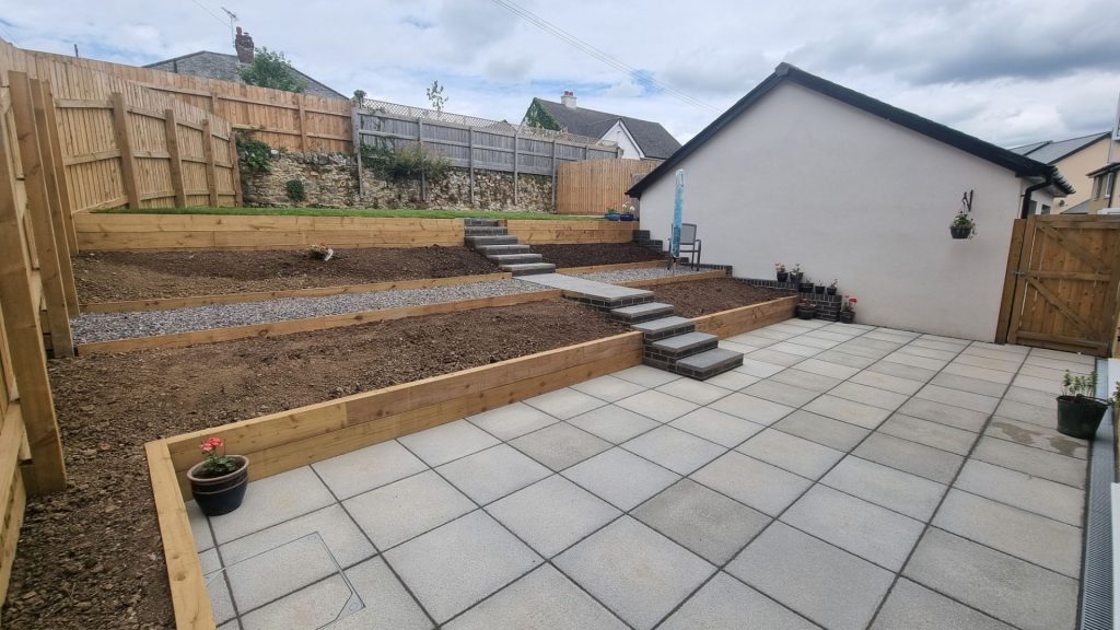 terraced garden, patio entertainment, smart design for chudleigh garden in devon. completed project showing full view from the rear patio, across from left. plenty of space to relax and entertain